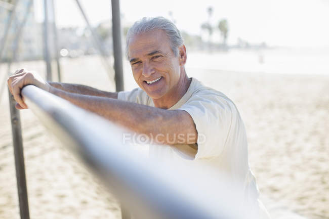 Retrato de homem sênior apoiando-se em bar na praia — Fotografia de Stock