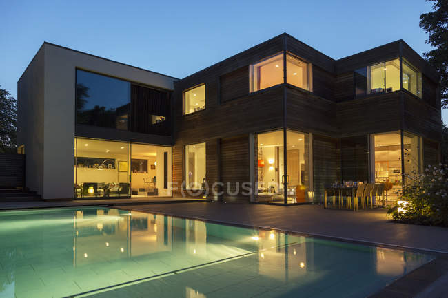 Maison moderne et piscine éclairée au crépuscule — Photo de stock
