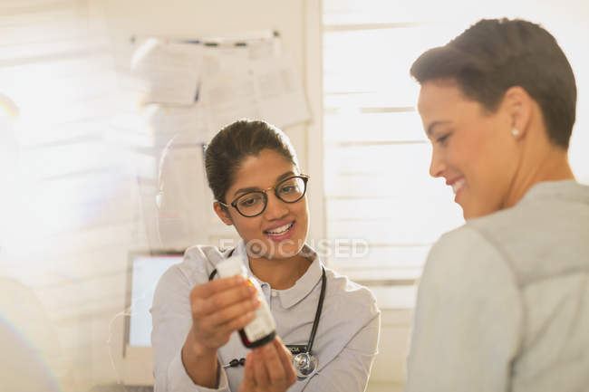 Female doctor showing cough syrup medicine to patient in examination room — Stock Photo
