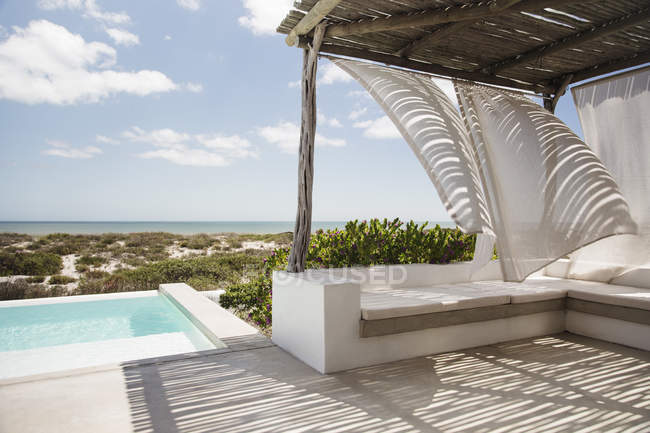Vorhänge wehen im Wind auf Luxus-Pool-Terrasse mit Blick auf das Meer — Stockfoto