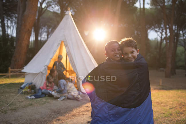 Boys wrapped in blanket at campsite — Stock Photo