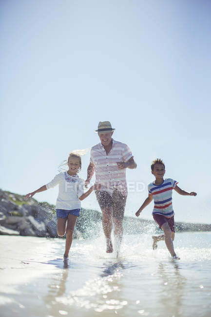 Família correndo na água na praia — Fotografia de Stock