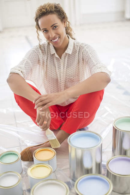 Mulher com vista para o espaço com latas de tinta perto — Fotografia de Stock