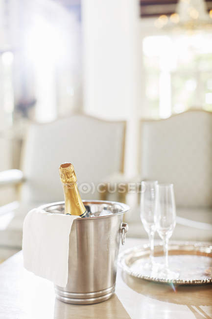 Champagne dans un seau d'argent à côté des flûtes à champagne — Photo de stock