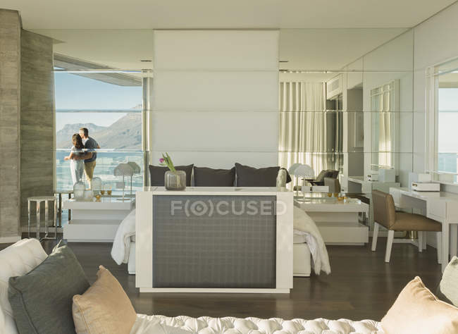 Відображення пари, яка дивиться на сонячний вид на океан з сучасного розкішного будинку вітрина балкона спальні — стокове фото