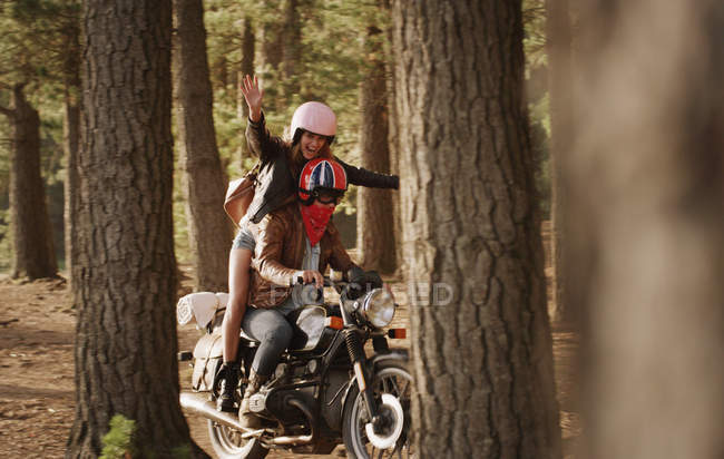 Ausgelassene junge Frau fährt Motorrad im Wald — Stockfoto