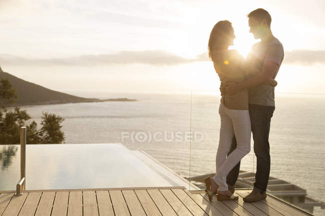 Couple on wooden deck overlooking ocean — Stock Photo