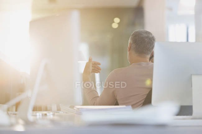 Бизнесмен жестикулирует за столом в солнечном офисе — стоковое фото