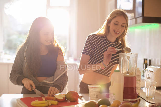 Ragazze adolescenti che fanno frullato in cucina soleggiata — Foto stock