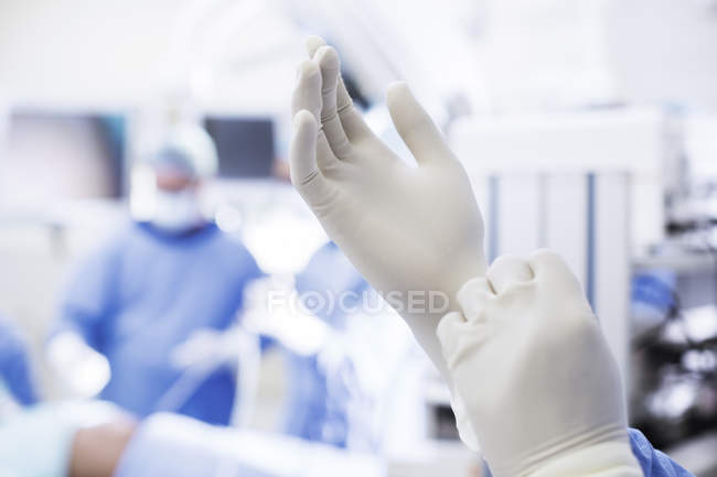 Крупним планом хірург кладе хірургічні рукавички в операційний театр — стокове фото
