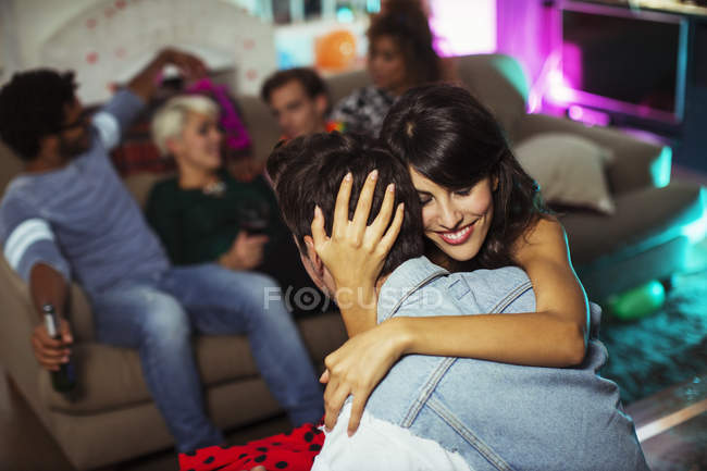 Couple hugging in living room at party — Stock Photo