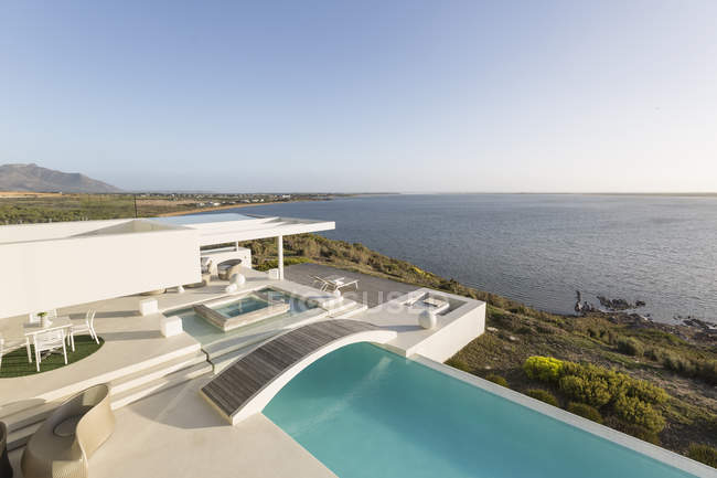 Soleada, tranquila casa de lujo moderna escaparate exterior con piscina infinita y vista al mar - foto de stock