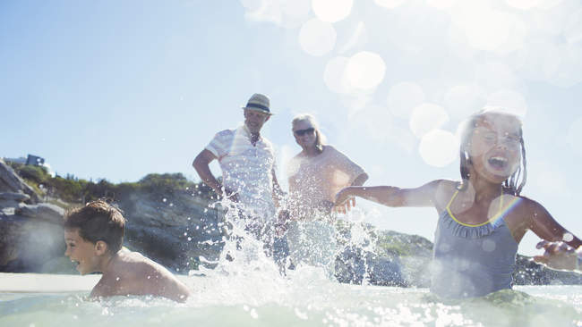 Family splashing each other on beach — Stock Photo