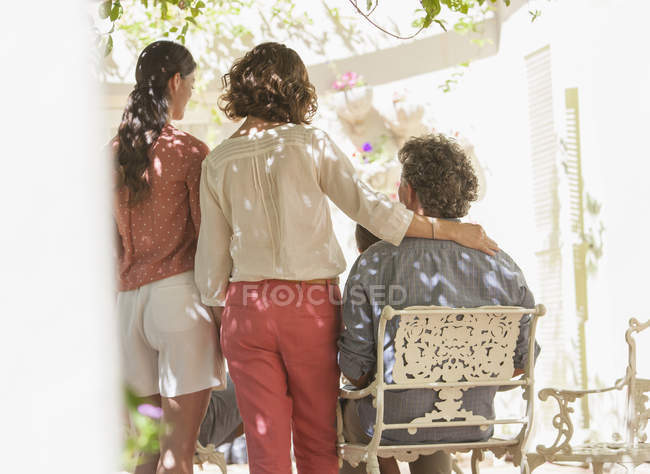 Vista trasera de la familia reunida alrededor de la mesa al aire libre - foto de stock