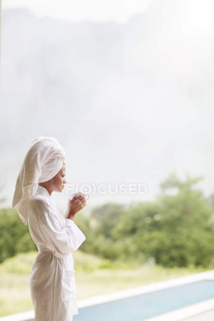 Жінка в халаті п'є каву на відкритому повітрі — стокове фото