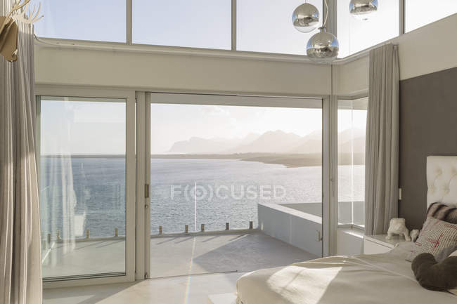 Sunny, tranquilo casa de luxo moderno vitrine interior quarto com vista para o mar — Fotografia de Stock