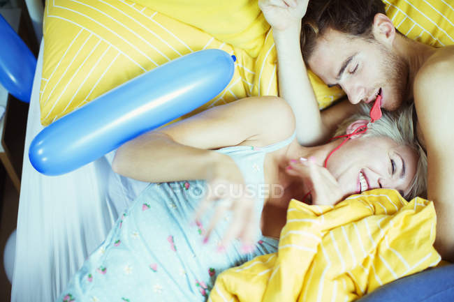 Casal brincando na cama com balões — Fotografia de Stock