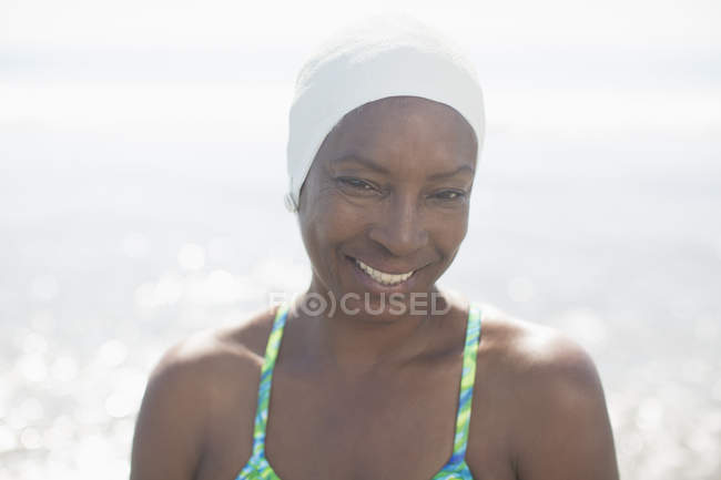 Retrato de mulher sorridente em touca de natação na praia — Fotografia de Stock