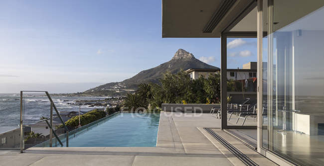 Vue sur la montagne et l'océan au-delà de la piscine extérieure de luxe vitrine extérieure — Photo de stock