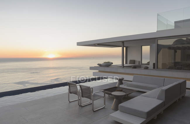 Vue du coucher du soleil sur l'horizon océanique depuis le patio extérieur moderne et luxueux de la maison — Photo de stock