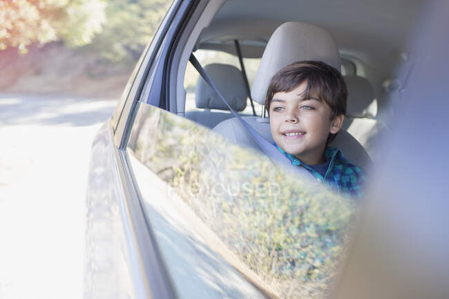 Joyeux garçon regardant par la fenêtre de la voiture — Photo de stock
