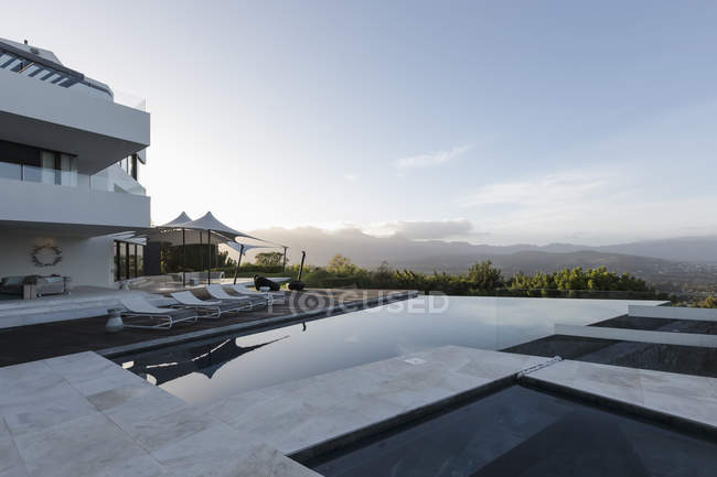 Tranquilo casa de luxo moderno vitrine exterior com piscina infinita e vista para a montanha — Fotografia de Stock