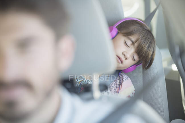 Дівчина з навушниками спить на задньому сидінні автомобіля — стокове фото