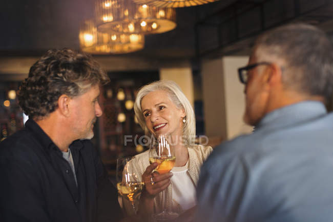 Друзі розмовляють і п'ють біле вино в барі — стокове фото
