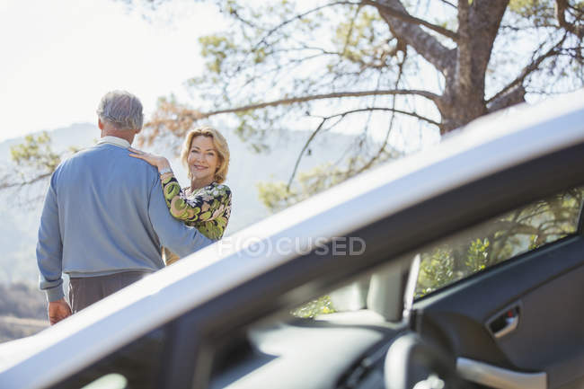 Couple aîné étreignant au bord de la route à l'extérieur de la voiture — Photo de stock