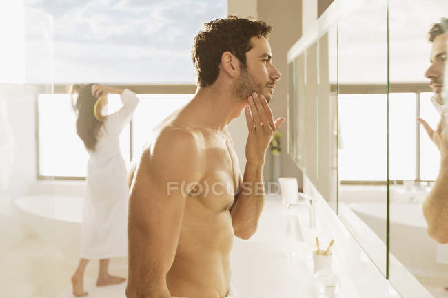 Мужчина проверяет бороду в зеркале ванной — стоковое фото