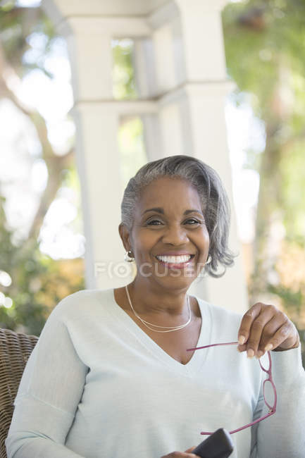 Ritratto di donna anziana felice che tiene gli occhiali all'aperto — Foto stock