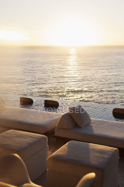 Sofás e piscina infinita com vista para o oceano — Fotografia de Stock