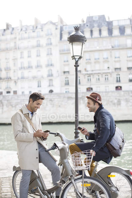 Empresarios con celulares en bicicletas a lo largo del río Sena, París, Francia - foto de stock