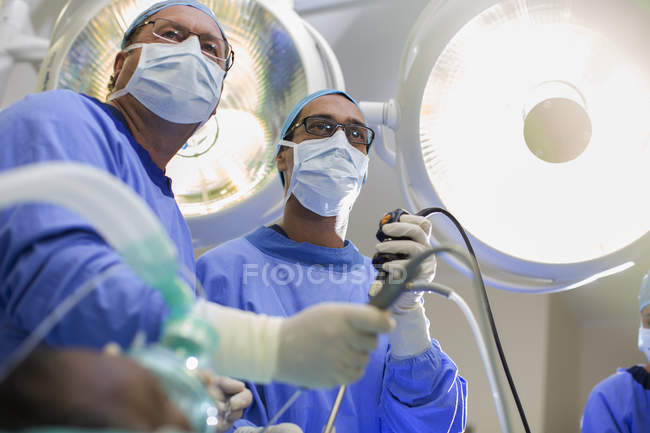 Низький кут зору двох хірургів, що тримають лапароскопічне обладнання в операційному театрі — стокове фото