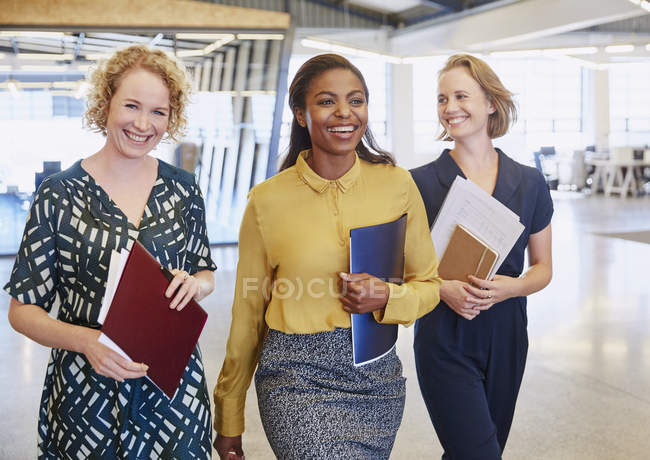 Mujeres de negocios sonrientes caminando en la oficina moderna - foto de stock