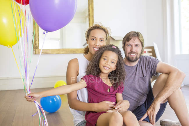 Family sitting in living space with balloons — Stock Photo