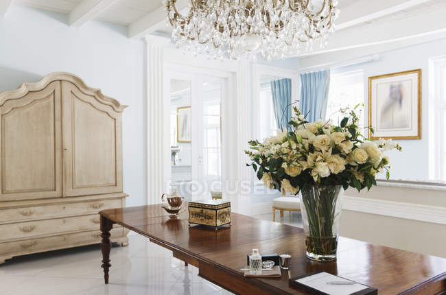 Kronleuchter über Rosenstrauß auf Tisch im Luxusfoyer — Stockfoto