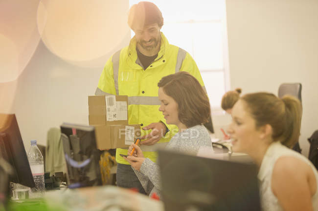 Zusteller liefert Paket an Geschäftsfrau im Amt aus — Stockfoto