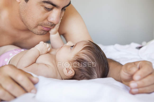 Батько захоплені чарівні дитини дівчина на ліжку — стокове фото