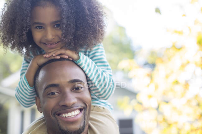 Retrato de sonriente padre con hija en hombros - foto de stock