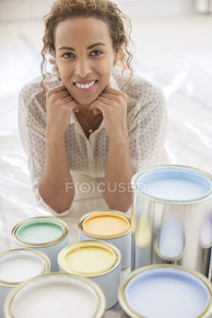 Mujer sentada frente a latas de pintura - foto de stock