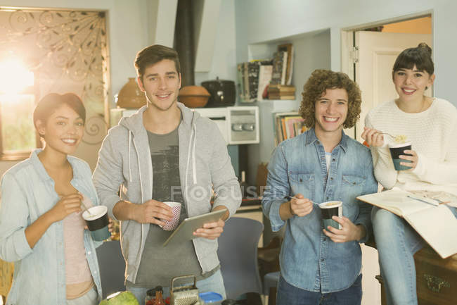 Portrait smiling young college student roommates studying eating instant noodles in apartment — Stock Photo