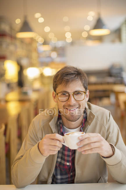 Счастливый молодой человек пьет кофе в кафе — стоковое фото