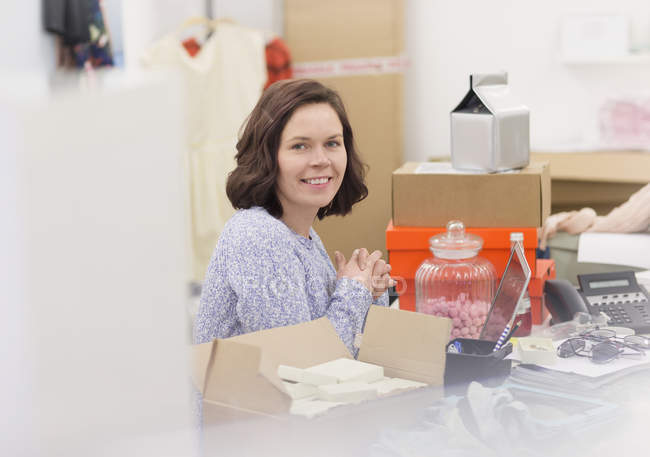 Portrait smiling fashion buyer at messy desk in office — Stock Photo