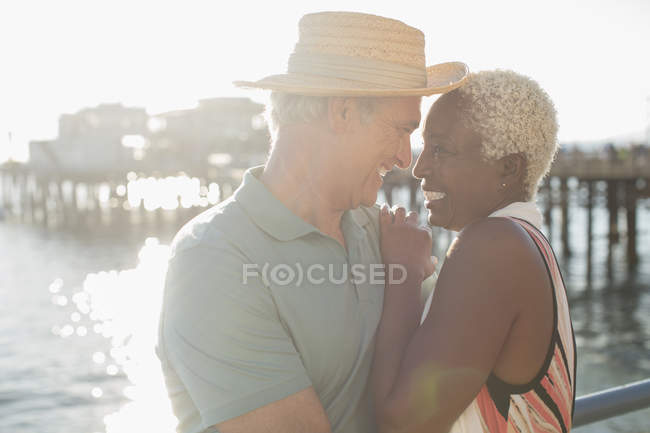 Старшая многорасовая пара обнимается на пирсе — стоковое фото
