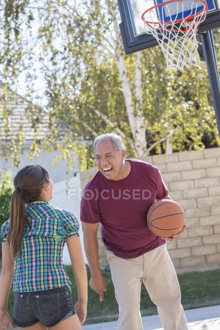 Abuelo y nieta jugando baloncesto en la entrada — Felicidad, infancia -  Stock Photo | #199390002