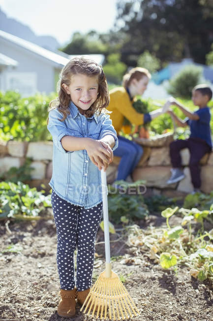 Girl holding rake in garden — Stock Photo