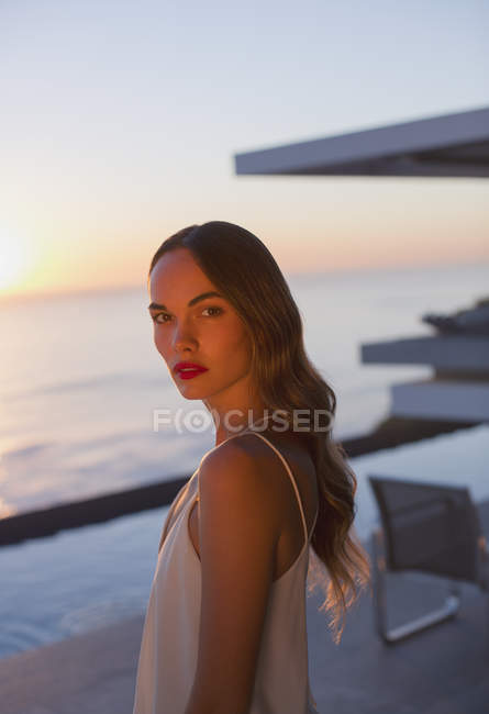 Retrato sério, bela mulher no pátio do pôr do sol com vista para o mar — Fotografia de Stock