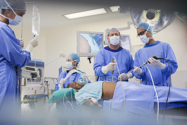 Equipo de cirujanos operando al paciente en el hospital - foto de stock