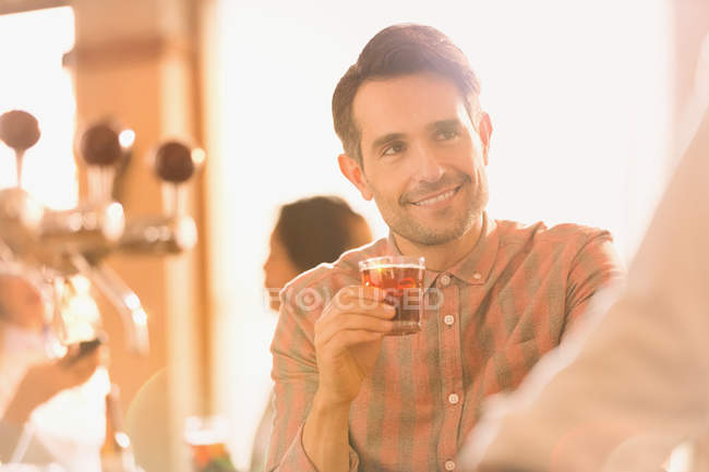 Усміхнений чоловік п'є коктейль у барі — стокове фото